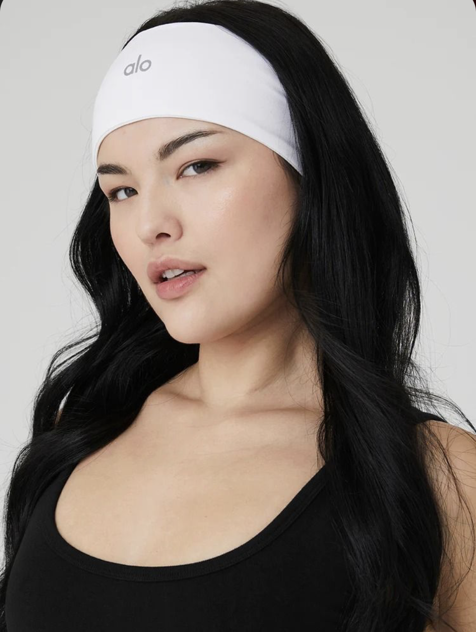 Model wearing an authentic white Alo Yoga headband and black tank top, part of The American Closet's in-stock Alo Yoga collection